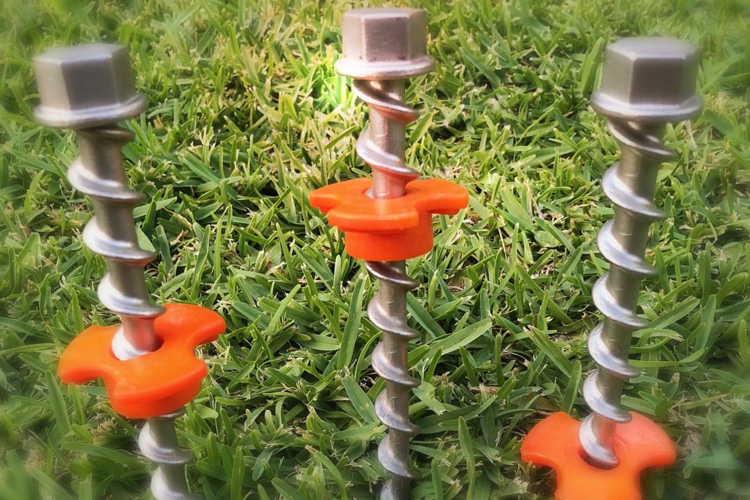 3 Ground dogs stainless steel screw placed on green lawn